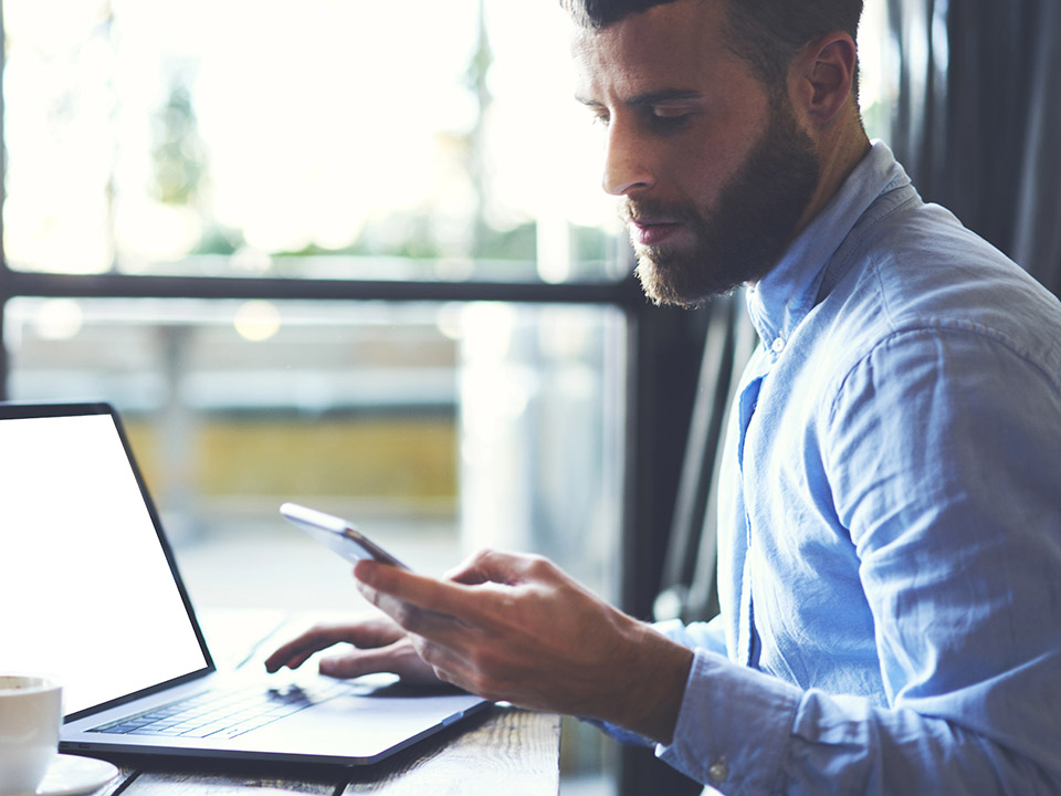 man working on phone and computer