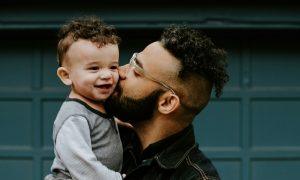 A Hispanic father embraces his son.