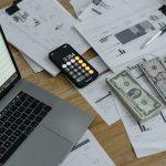 Dinero en efectivo, gráficos financieros y calculadora que ilustran el impacto de los aranceles y precios altos en Estados Unidos