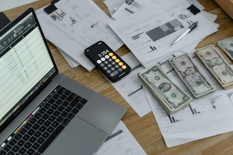 Dinero en efectivo, gráficos financieros y calculadora que ilustran el impacto de los aranceles y precios altos en Estados Unidos