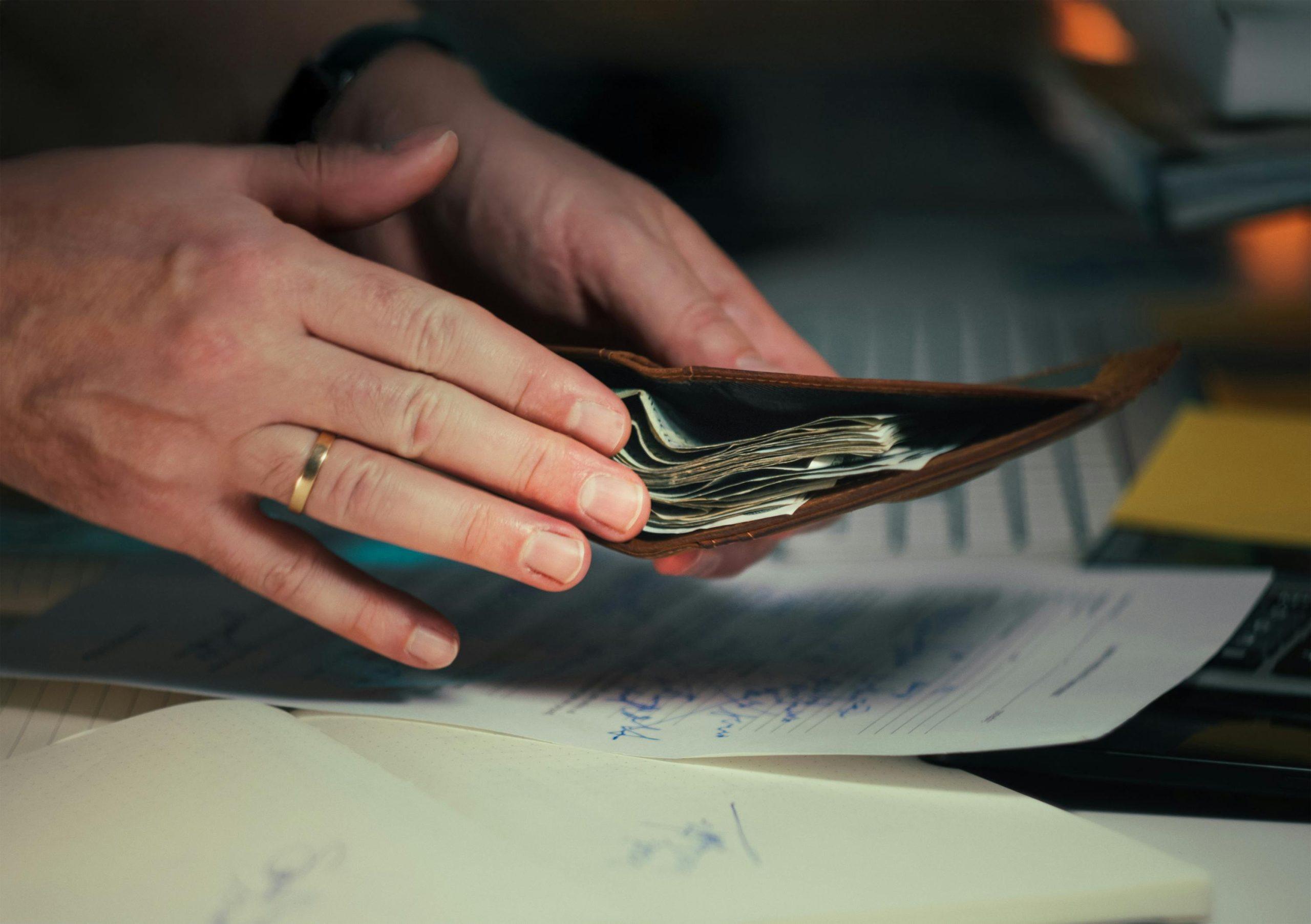 Una mano de un hombre ahorrando para llegar a 5 metas financieras 2026